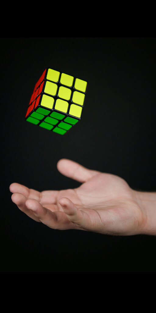 Hand wirft Rubikwürfel in die Luft